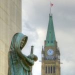 The statue Ivstitia (Justice) looks outward from the Supreme Court of Canada, with the Peace Tower in the near distance.