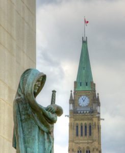 The statue Ivstitia (Justice) looks outward from the Supreme Court of Canada, with the Peace Tower in the near distance.